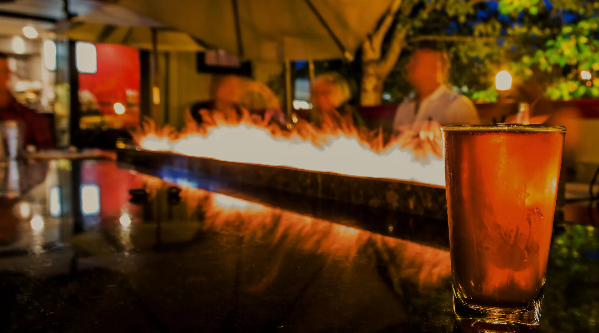 A pint of amber beer on the patio beside the Fireside Grill's fire table at dusk